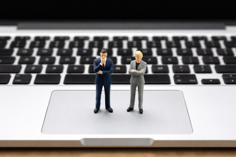 Miniaturowi biznesmeni przy laptopie